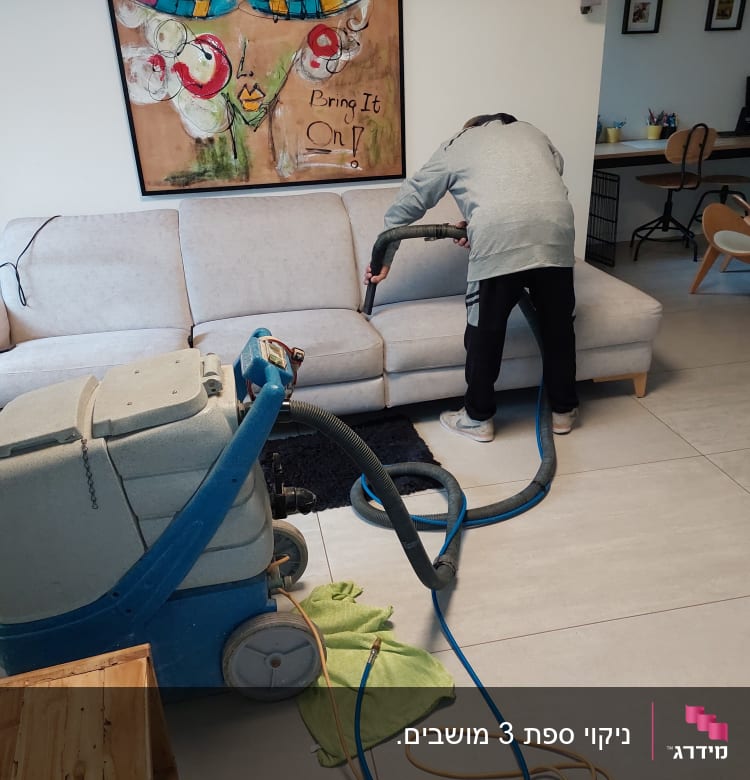 אדם מנקה ספה עם מכונת ניקוי גדולה